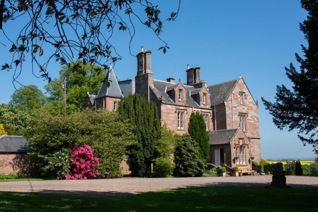 an old castle with pink flowers in front of it at Chirnside Hall Hotel in Chirnside