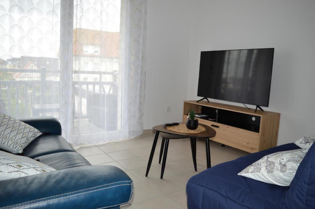 salon z kanapą i telewizorem z płaskim ekranem w obiekcie Appartement spacieux avec balcon - à 50m de la plage w mieście Courseulles-sur-Mer