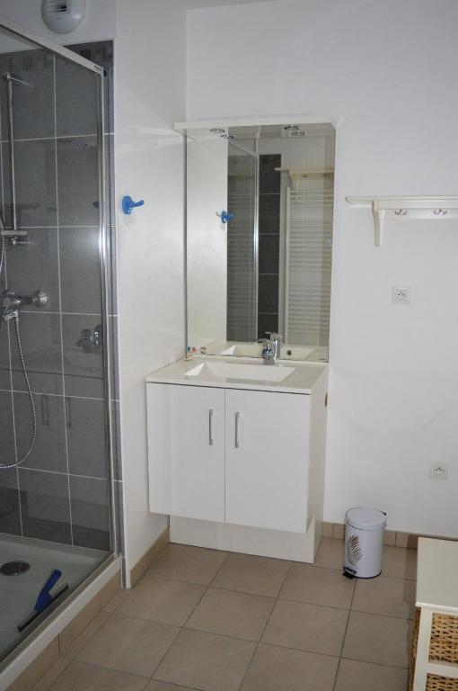 W łazience znajduje się biała umywalka i prysznic. w obiekcie Appartement spacieux avec balcon - à 50m de la plage w mieście Courseulles-sur-Mer