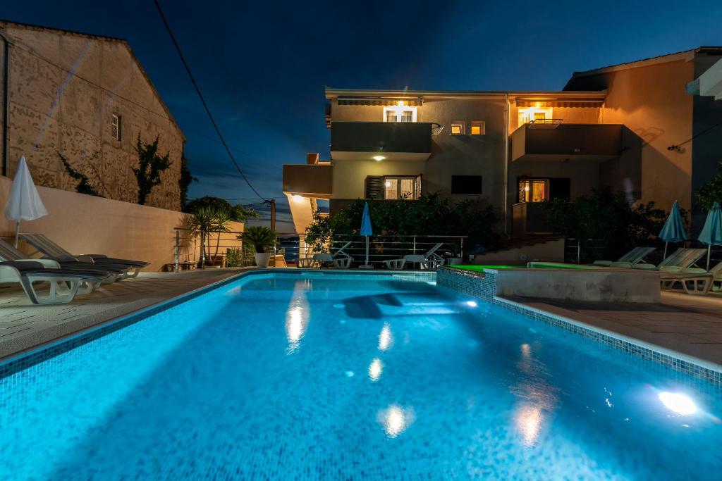 a swimming pool in front of a house at night at Apartments Villa Magdalena in Trogir