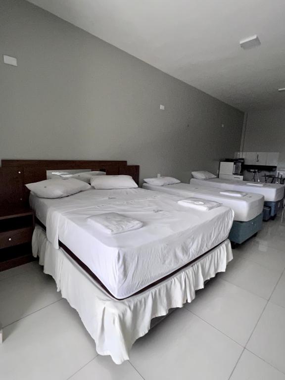 three beds are lined up in a room at Pinheiro Flat Hotel in Ibiapina