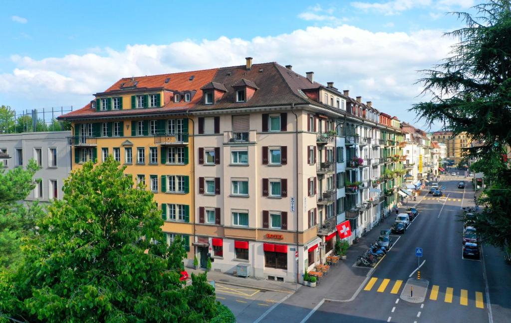 a building with a red roof on a city street at Hotel La Balance self check-in in Biel