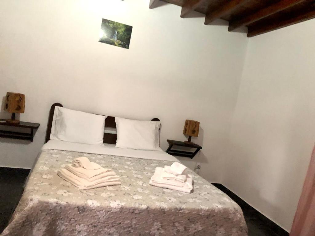 a bedroom with a bed with two towels on it at Casa do vermelho in Povoação