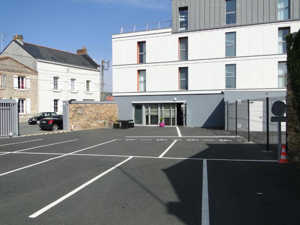 um parque de estacionamento vazio em frente a um edifício em The Originals Access, Hôtel Cholet Gare em Cholet