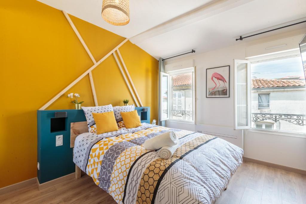 - une chambre avec un lit et un mur jaune dans l'établissement Cosy Apparts Saintes, à Saintes