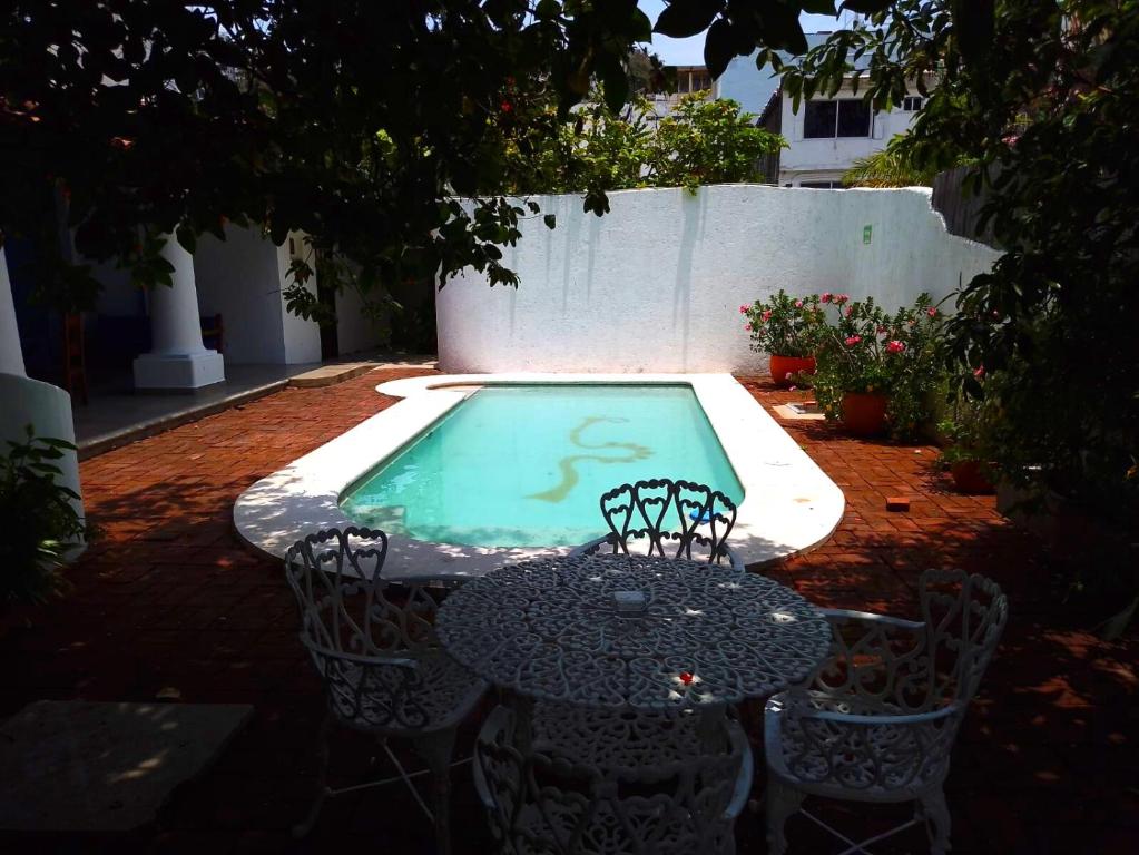 einen Tisch und Stühle neben einem Pool in der Unterkunft Hotel Misión y Spa in Acapulco