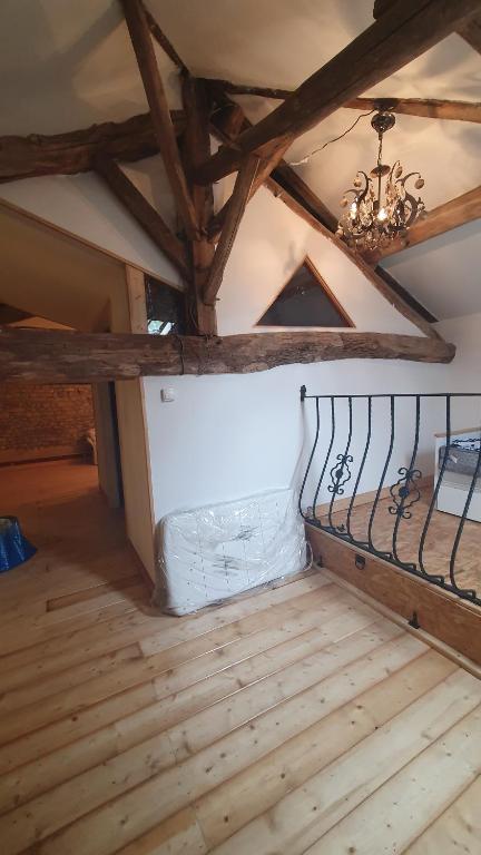 an attic room with a chandelier and wooden floors at Chateau Mano in Mairé-lʼEveseault