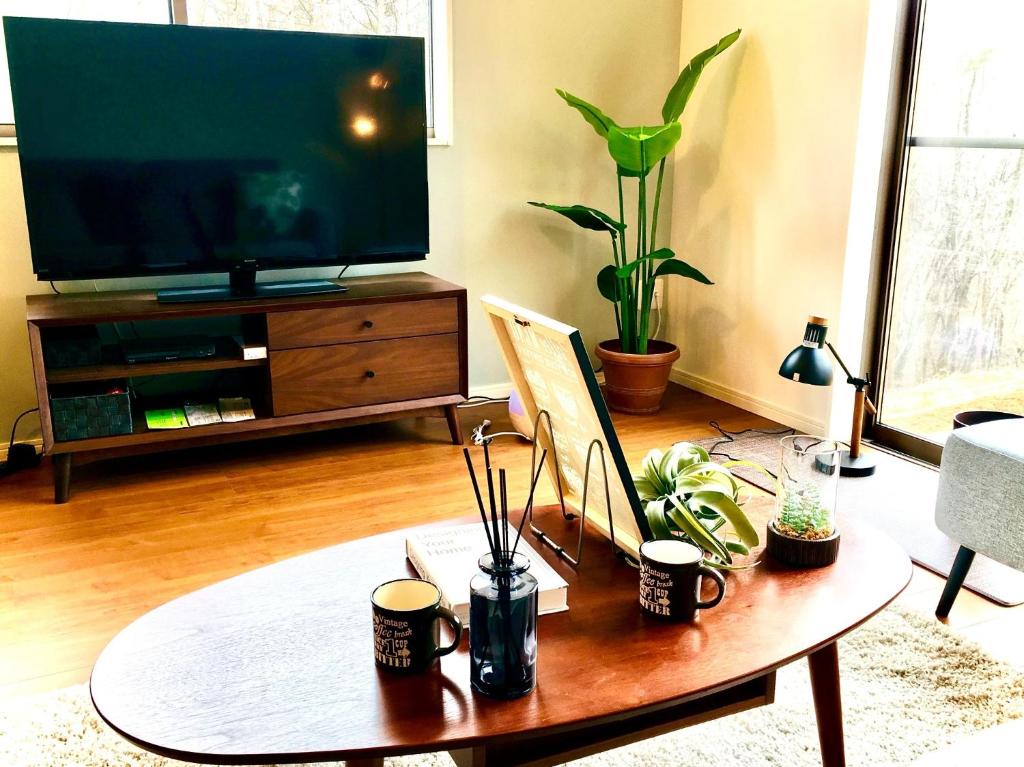 ein Wohnzimmer mit einem Couchtisch und einem Flachbild-TV in der Unterkunft Yatsugatake Villa Masaki - Vacation STAY 74331v in Hokuto