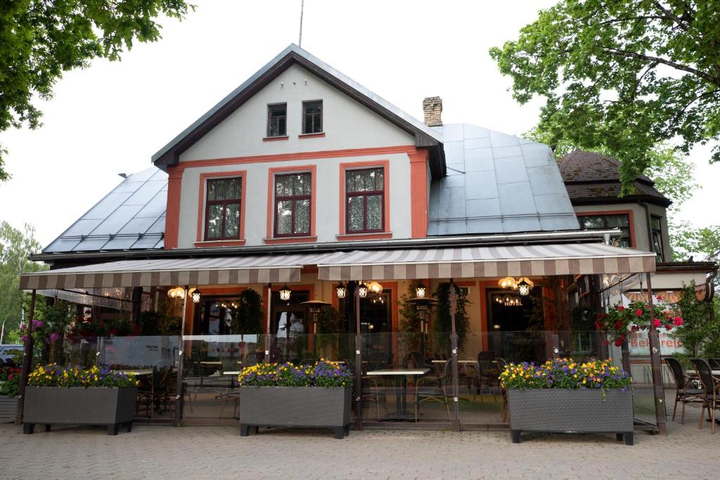 ein Restaurant mit Tischen und Blumen vor einem Gebäude in der Unterkunft City Center Kaķis B&B in Sigulda