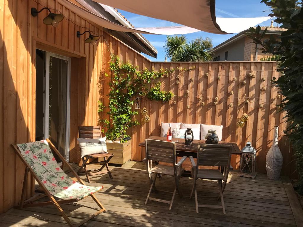 d'une terrasse avec une table, des chaises et une clôture. dans l'établissement Cocon entre presqu'île du Cap Ferret et plages océanes - terrasse - 1 vélo gratuit, à Arès