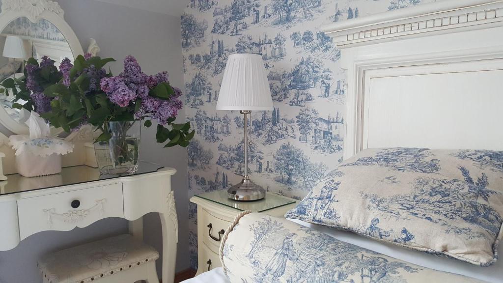 um quarto com papel de parede azul e branco com uma cama e flores em Brandon View House B&B em Graiguenamanagh