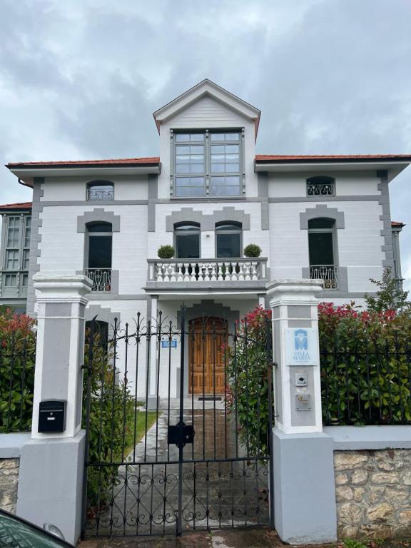 Uma casa branca com um portão à frente. em Villa Marta Casa de Indianos Passive House em Villanueva de Ardisana