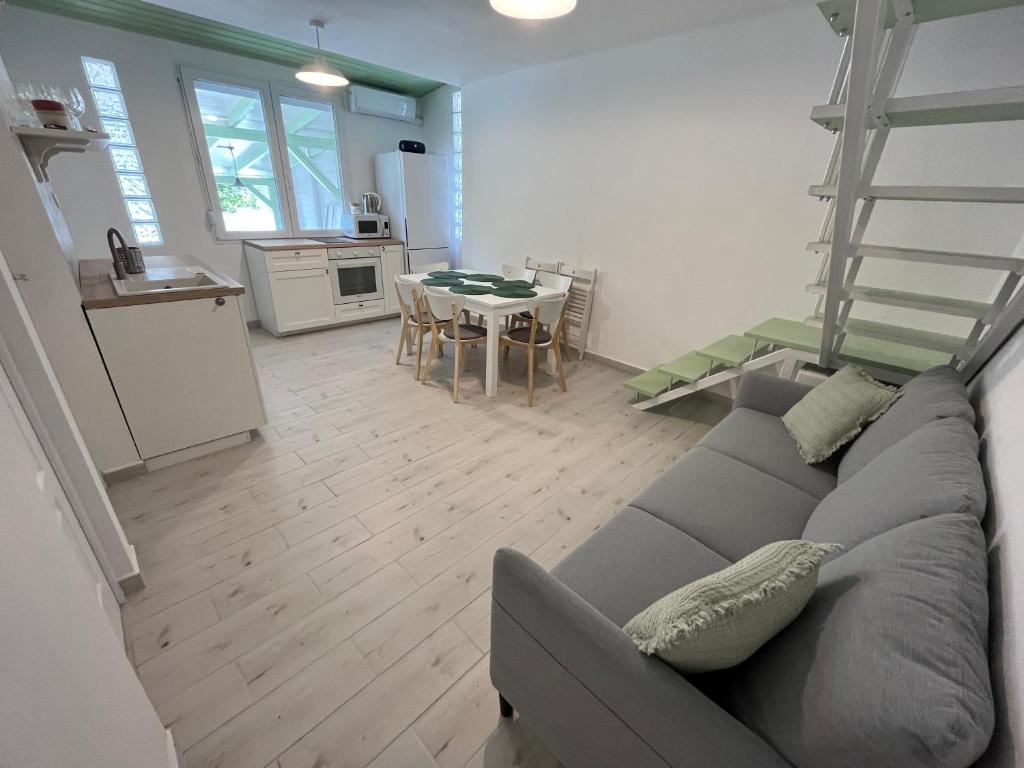 salon z szarą kanapą i kuchnią w obiekcie Helló Zsóry Apartman w Mezőkövesd