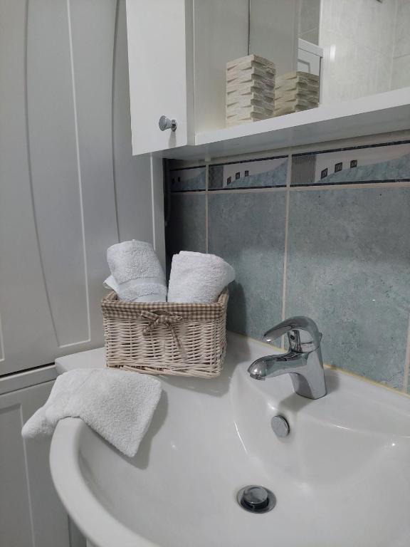 a bathroom sink with a basket of towels on it at Apartman Sany in Bihać