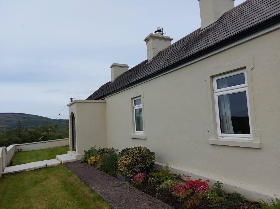 uma casa branca com uma janela e algumas flores em Patricia’s Country Cottage em Sligo