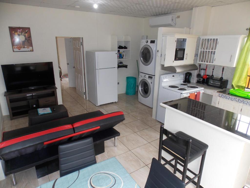 a living room with a kitchen with a couch and appliances at Stewart Apt- Trincity, Airport, Washer, Dryer, Office, Cable , WiFi in Trincity 