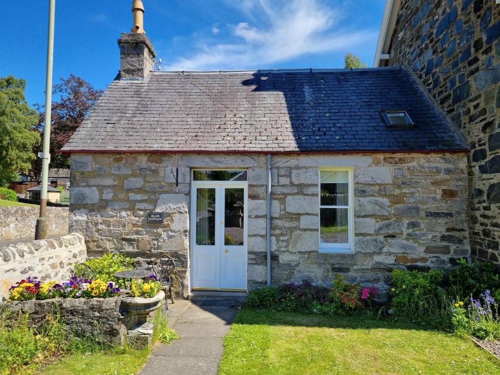 Cabaña de piedra antigua con puerta blanca en Cosy peaceful one-bedroom cottage in Pitlochry, en Pitlochry