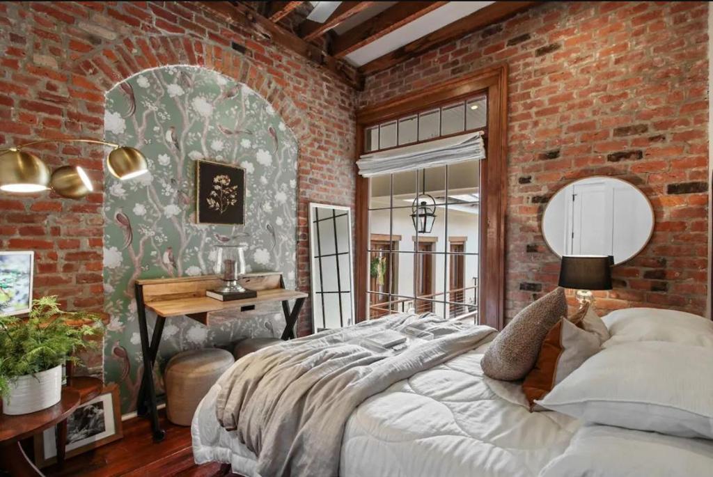 um quarto com uma cama grande numa parede de tijolos em Historic Garden District 5BR with Parking and Balcony em Nova Orleans