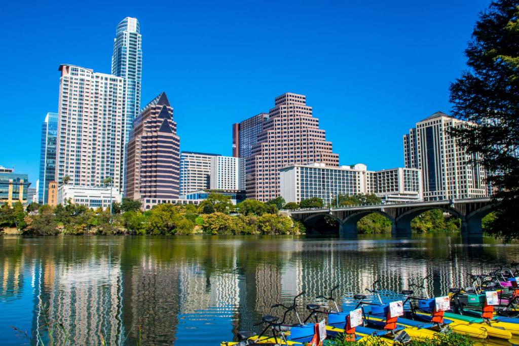 a city skyline with boats in a river with a bridge at Hotel Van Zandt in Austin