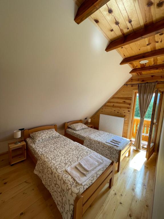 a bedroom with two beds and a wooden ceiling at Mokrogorski konaci in Mokra Gora