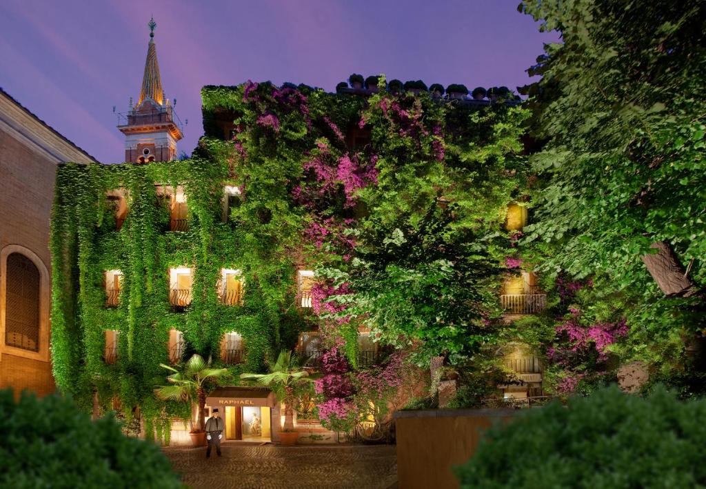 a building covered in green ivy with a clock tower at Bio Hotel Raphael - Relais & Châteaux in Rome