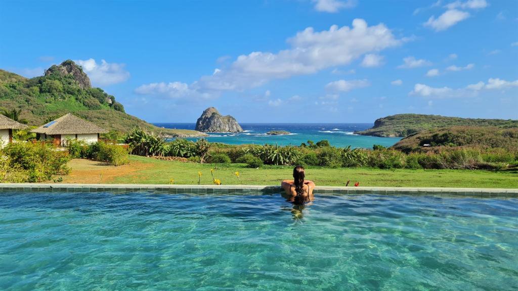 um homem na água numa piscina com vista para o oceano em NANNAI Noronha Solar Dos Ventos em Fernando de Noronha