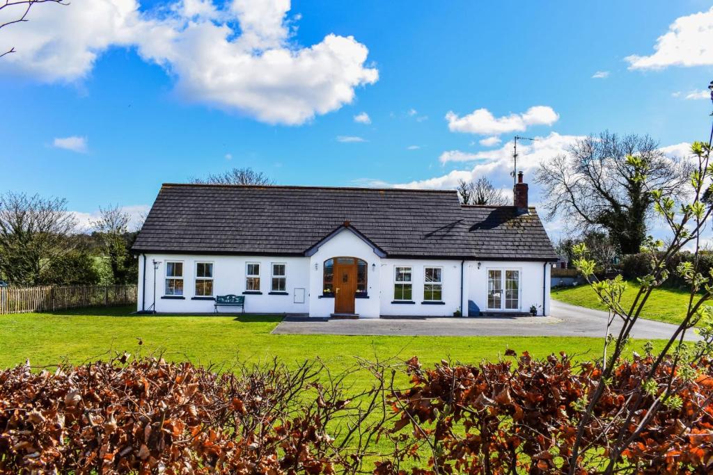 una casa blanca con techo negro en The Heights & Hollows Farmhouse, Saul, Downpatrick, SLEEPS 14, en Downpatrick
