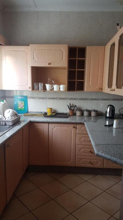 a kitchen with wooden cabinets and a counter top at Broadhurst Homestay in Gaborone