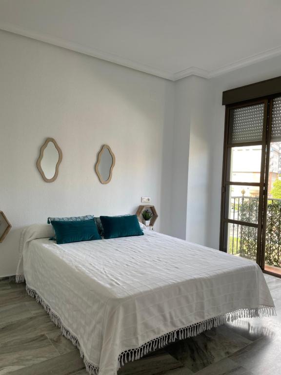 1 dormitorio blanco con 1 cama grande con almohadas azules en Apartamento turístico La Joya, en Huelva