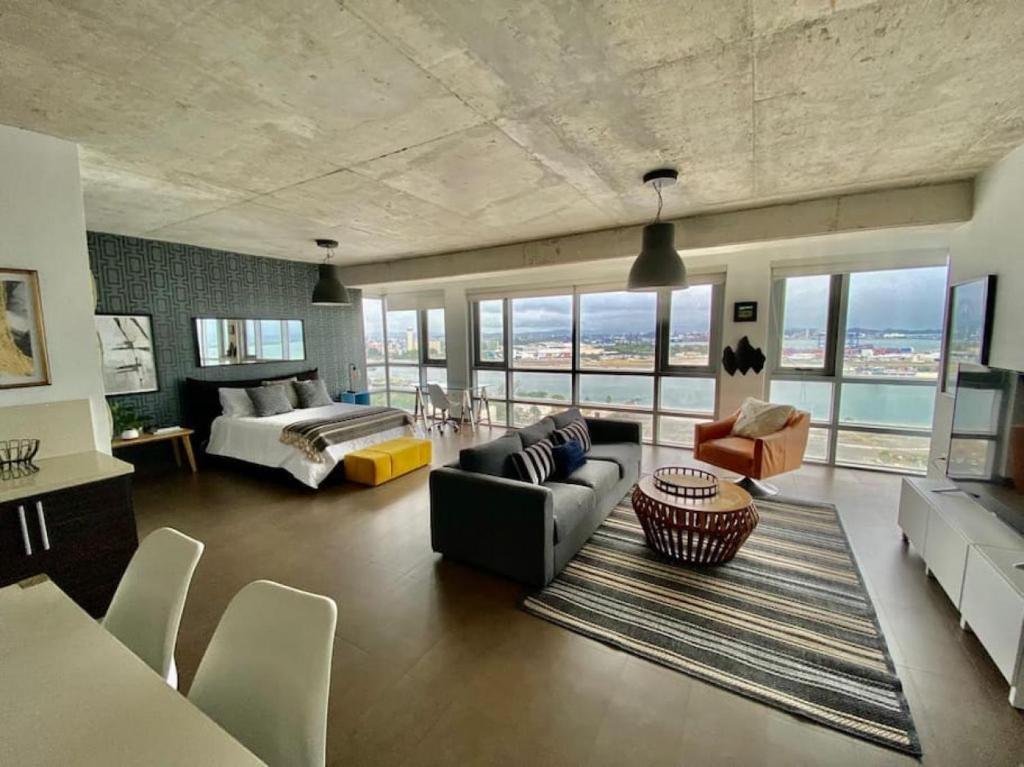 KASA Skyview Luxury Loft Style 15th floor Condo في سان خوان: غرفة معيشة كبيرة مع أريكة وسرير