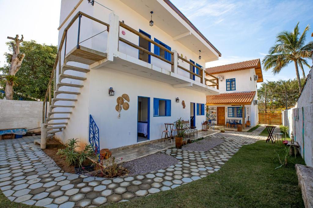 une maison blanche avec des fenêtres bleues et des escaliers dans l'établissement QUINTAL DO SON CHALÉS, à Ubatuba
