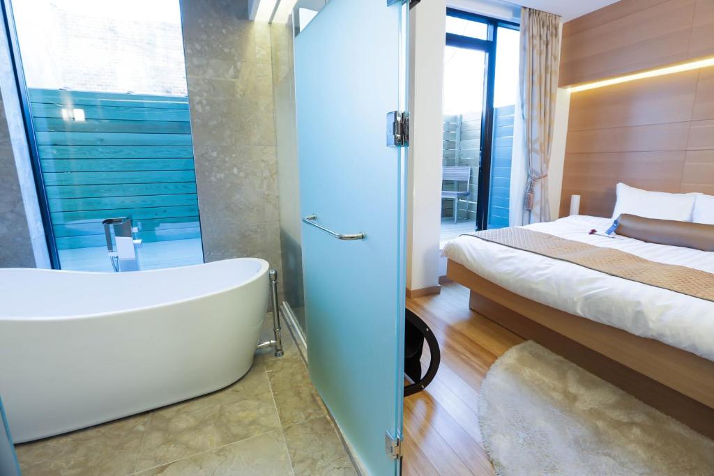 ein Badezimmer mit einer Badewanne, einem Bett und einer Badewanne in der Unterkunft The One Boutique Hotel in Queens