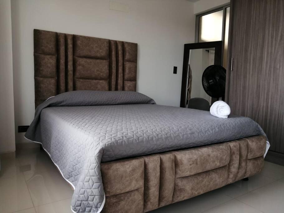 una camera da letto con un grande letto con una grande testiera di Apartamento de lujo , con linda vista, cuarto piso a Cartago