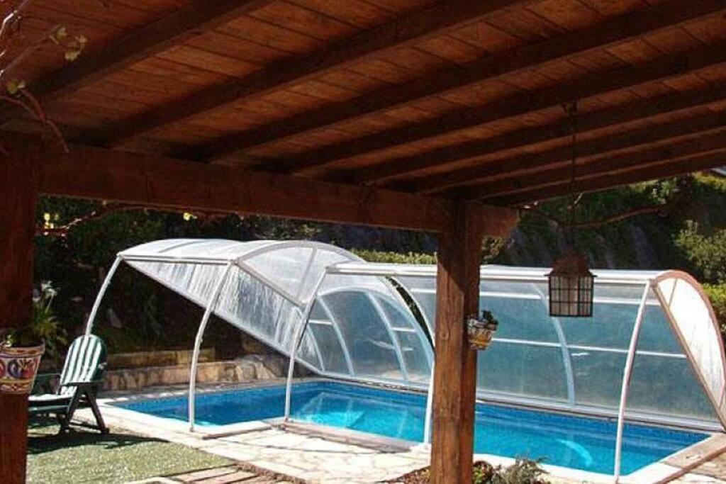 uma piscina sob uma pérgula de madeira com uma piscina em casa a 50 metros de playa con piscina cubierta em Liencres