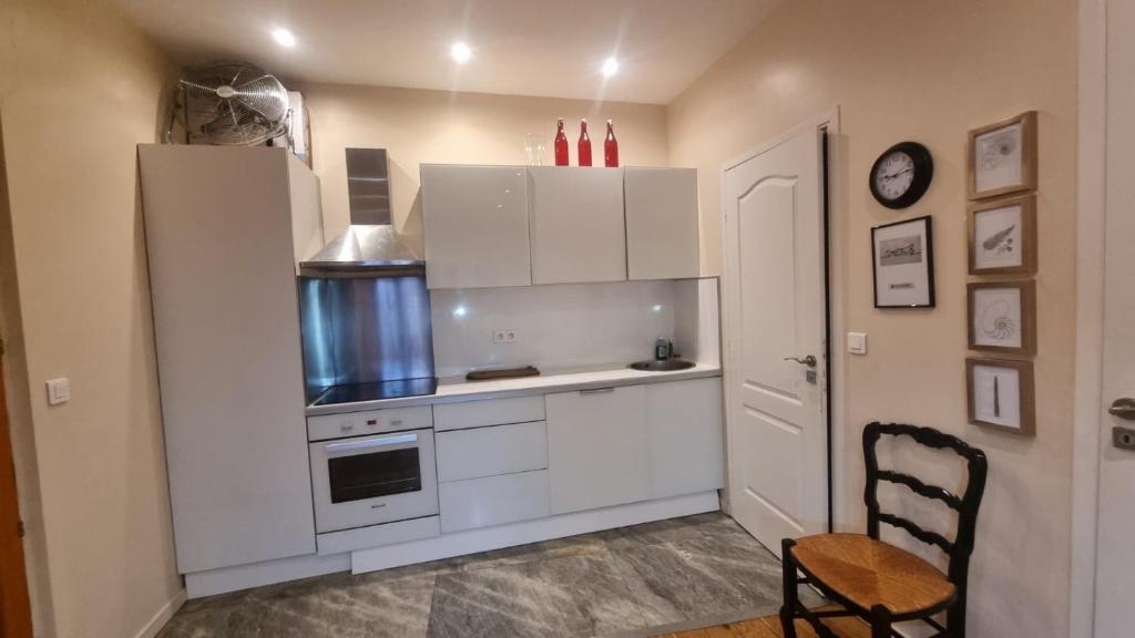 - une cuisine avec des placards blancs, une cuisinière et une chaise dans l'établissement Appartement en plein cœur de vieille Nice, à Nice