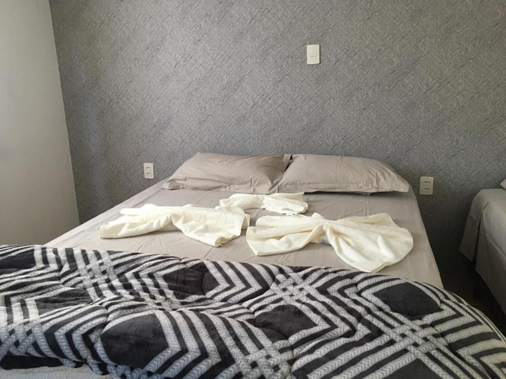 a bed with two sheets and a blanket on it at Aconchego das flores in Campos do Jordão