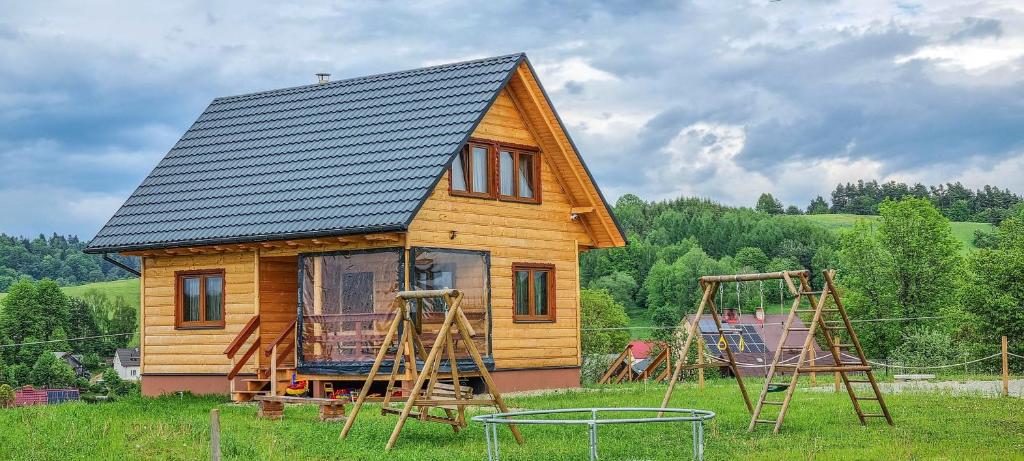 Domki Na Szlaku Bieszczady في Uherce Mineralne: منزل صغير مع ملعب و مرجيحة