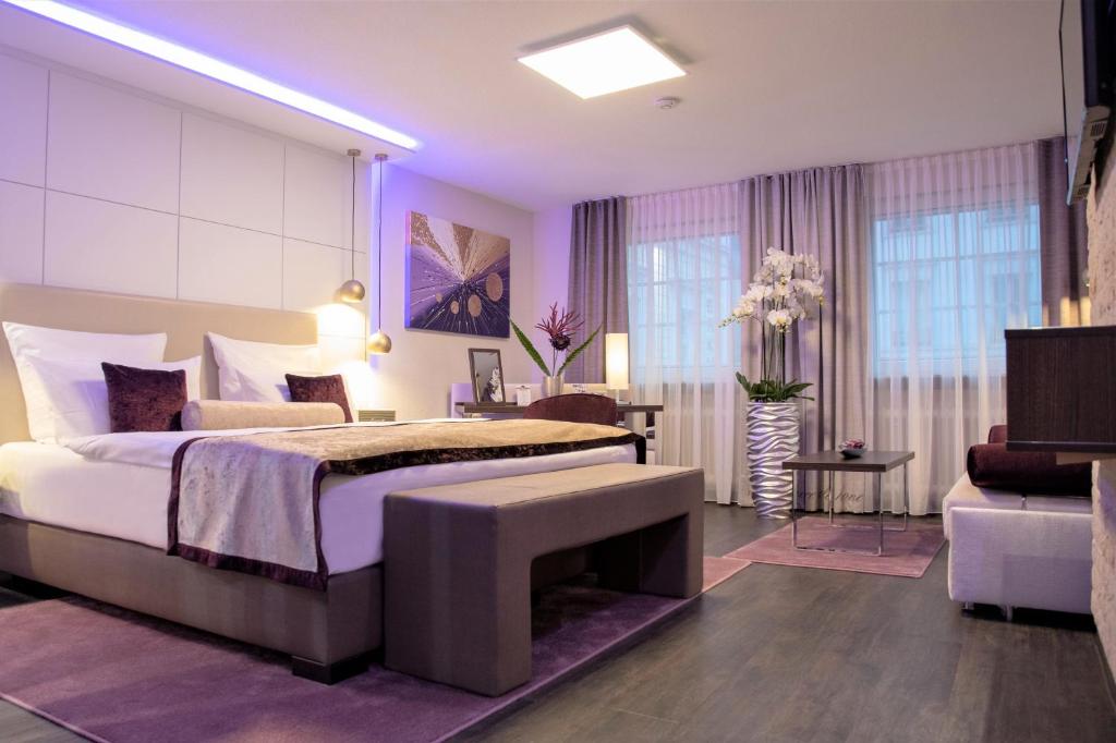 una camera con un grande letto con una panca di Hotel Merkur - Superior a Baden-Baden