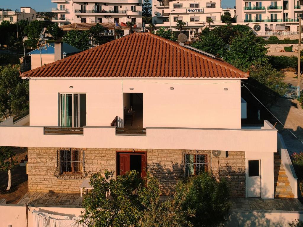 une maison blanche avec un toit rouge dans l'établissement Guesthouse Dollomaja Ksamil, à Ksamil
