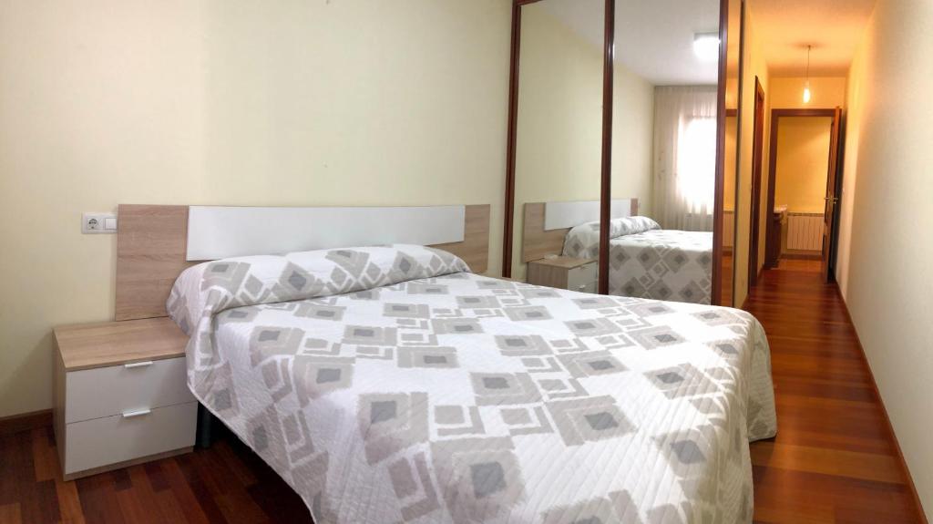um quarto com uma cama com um edredão branco e cinzento em Vivenda da Avoa em Monforte de Lemos