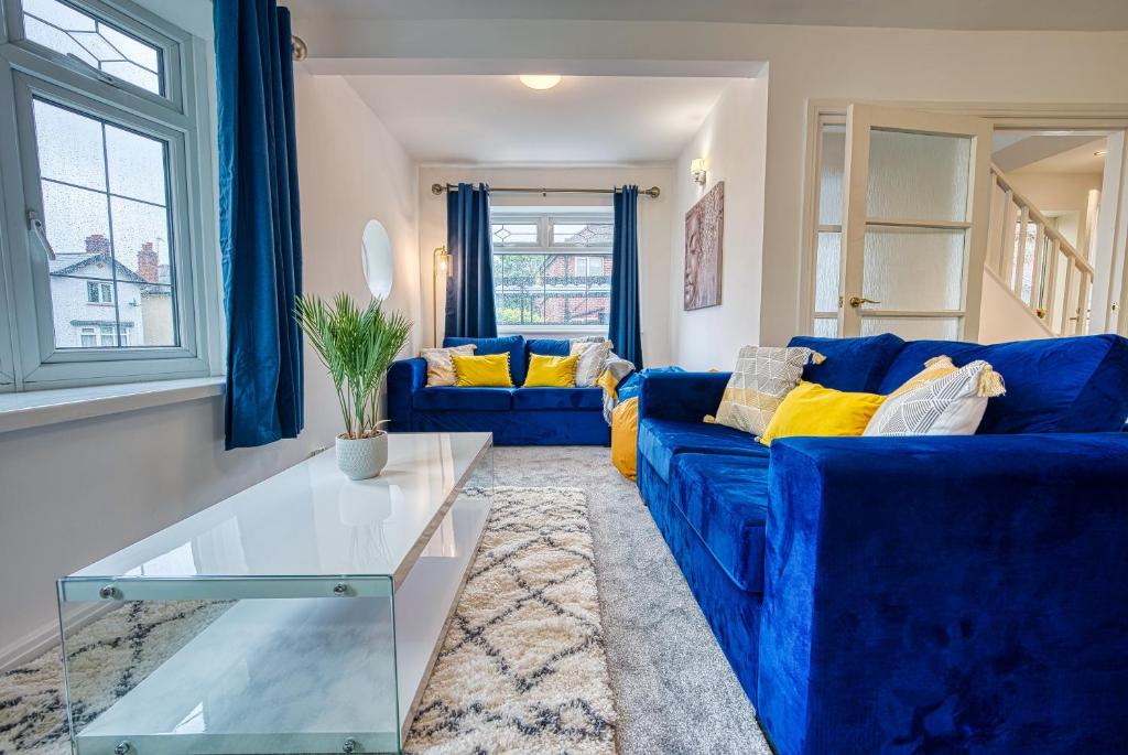 ein Wohnzimmer mit einem blauen Sofa und einem Glastisch in der Unterkunft Modern 3 Bedroom 2 Bath House with Parking by 360Midlands Wednesbury, Birmingham in Birmingham