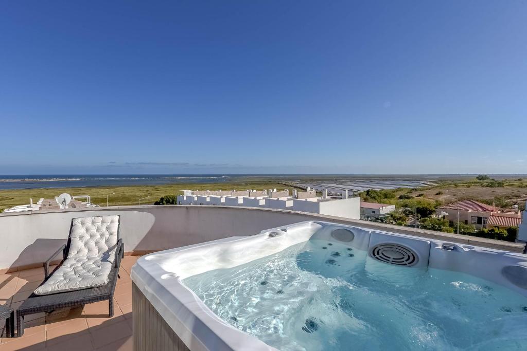 een jacuzzi op een balkon met een stoel bij Penthouse Quilha in Fuzeta