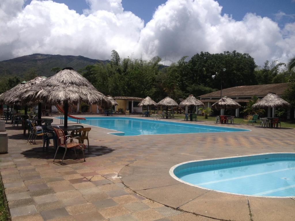 una piscina con mesas, sillas y sombrillas en Hotel Tacuara, en Guaduas