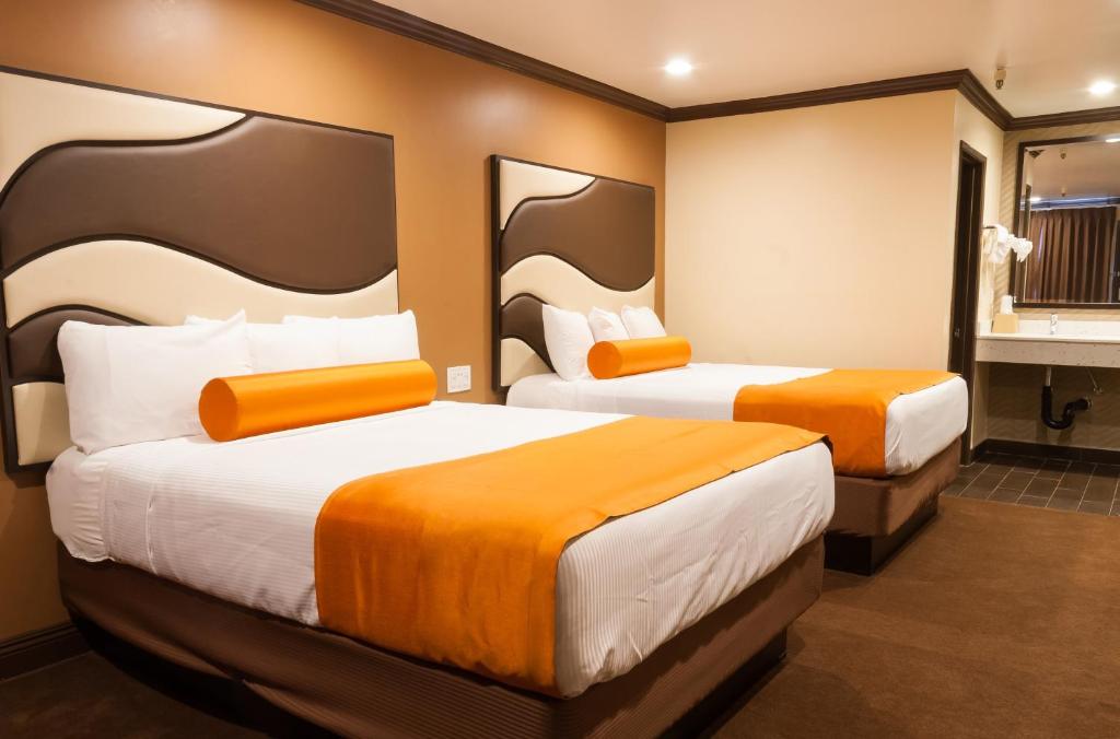 Cette chambre d'hôtel comprend 2 lits avec des draps orange. dans l'établissement Redondo Pier Inn, à Redondo Beach