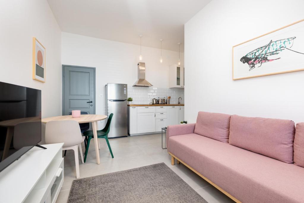 a living room with a pink couch and a kitchen at Apartments Cukar in Punat