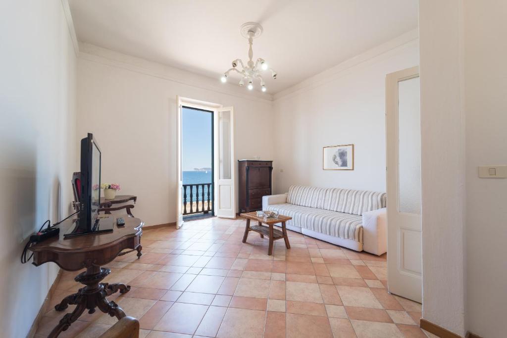 een woonkamer met een witte bank en een televisie bij Seaview Alghero Apt in Alghero