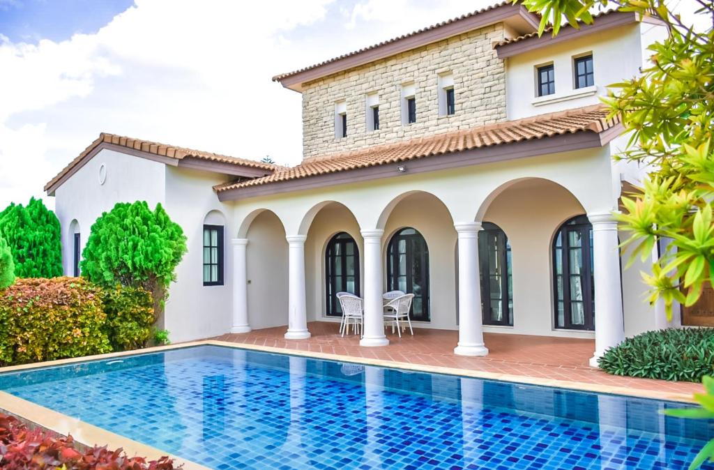 a villa with a swimming pool in front of a house at My Ozone Pool Villa KhaoYai in Pak Chong