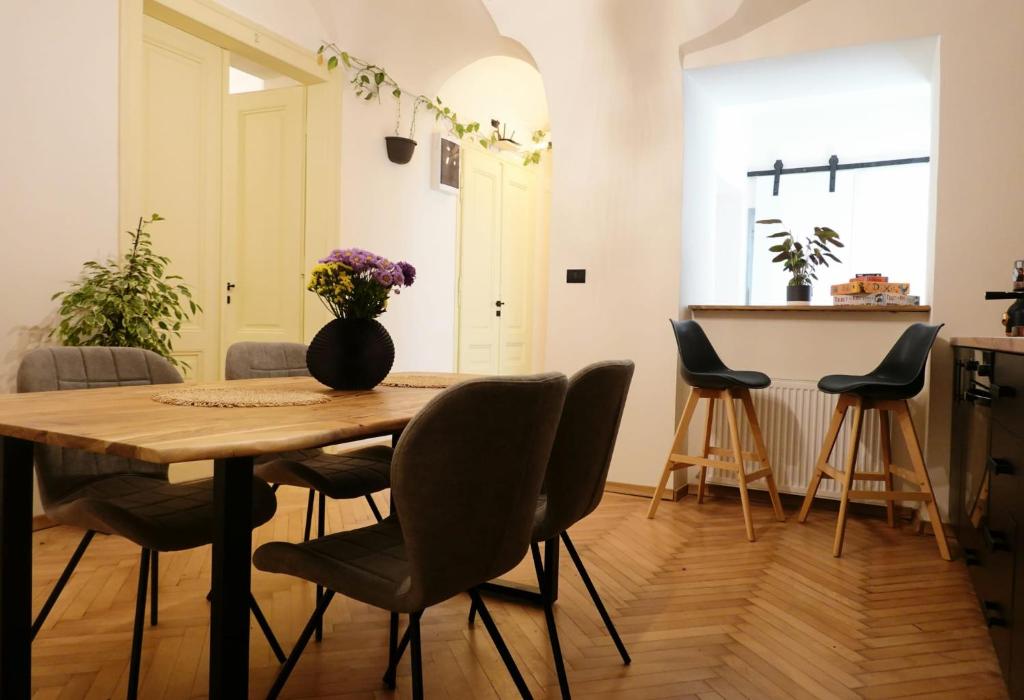 stół jadalny z krzesłami i wazon kwiatów w obiekcie The Industrique Home - 3 Bedroom Apartment w mieście Timişoara