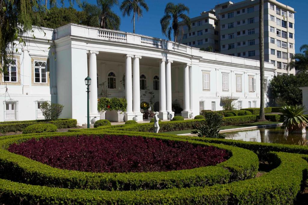 a large garden with flowers in front of a large building at Hotel Solar do Império in Petrópolis
