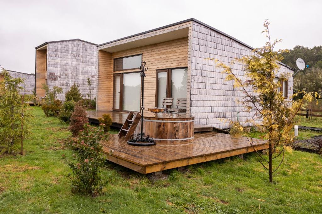 ein Haus mit einem Whirlpool auf einer Holzterrasse in der Unterkunft Cabañas Arrayanes de Huillinco en Chiloé in Chonchi